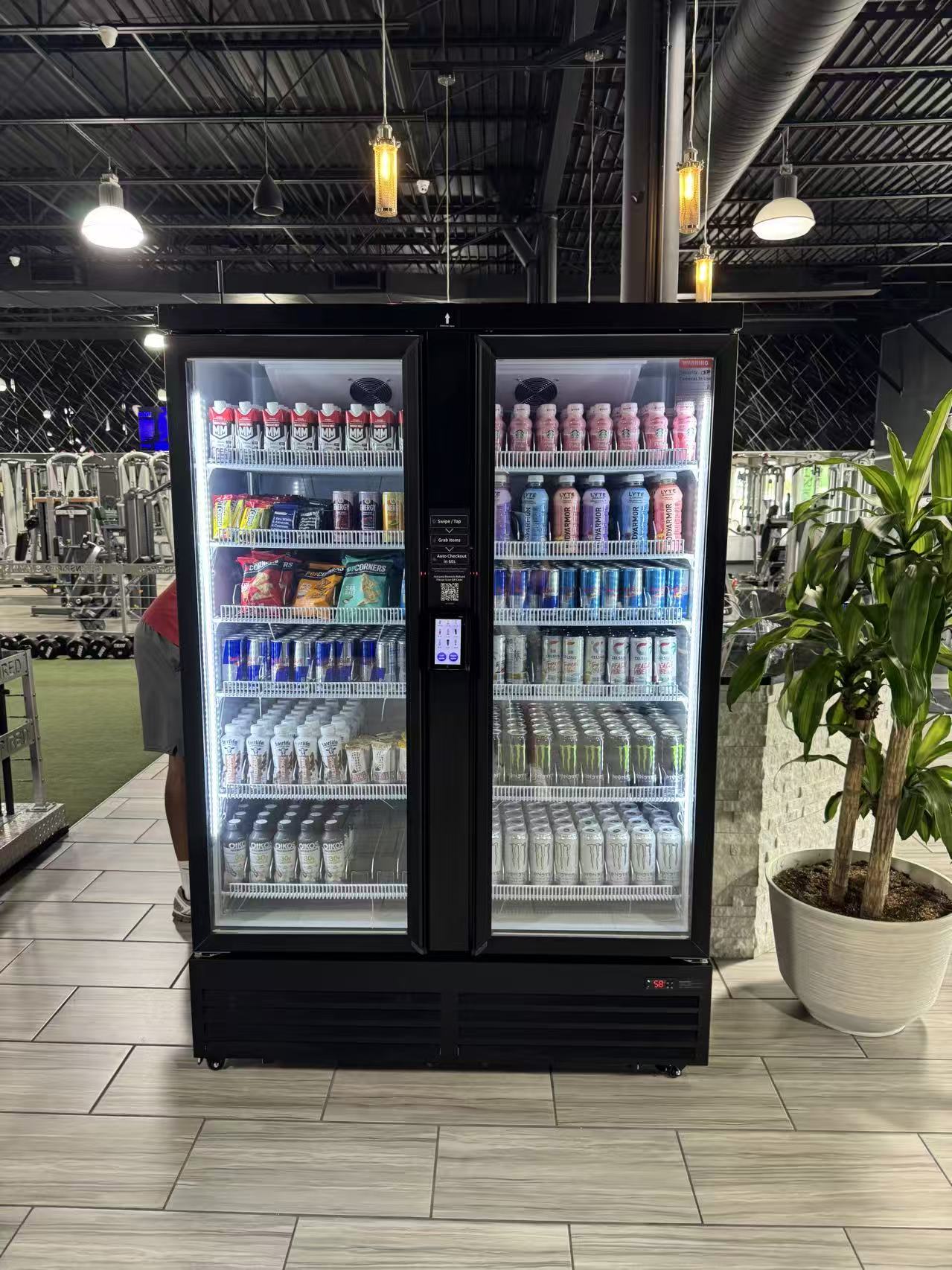 Smart cooler in a gym stocked with drinks and snacks